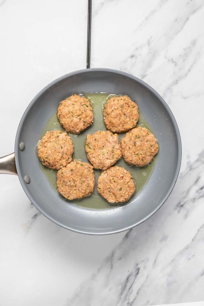 tuna potato patties cooking in a skillet with olive oil