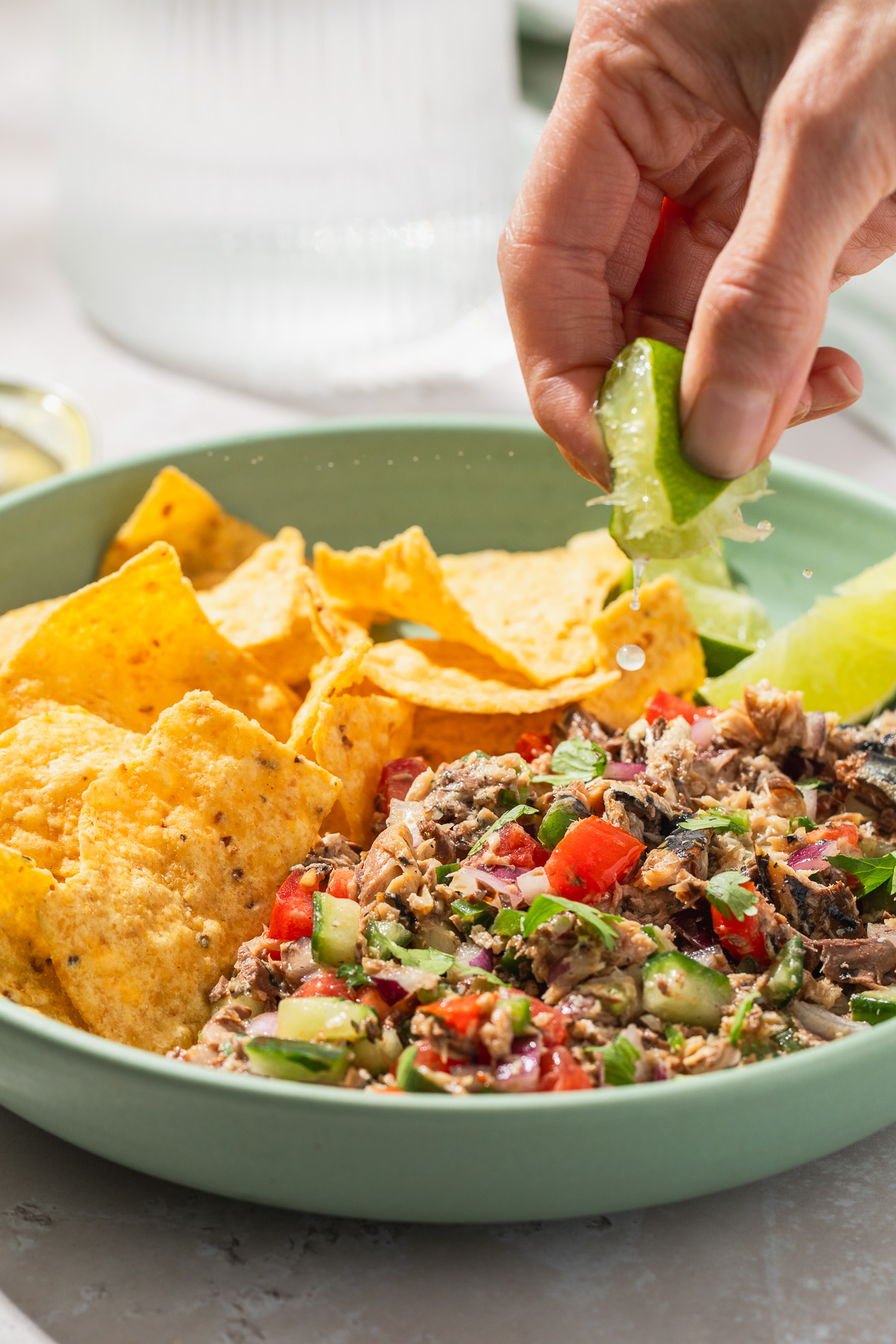 Lime wedge being squeezed over sardine ceviche