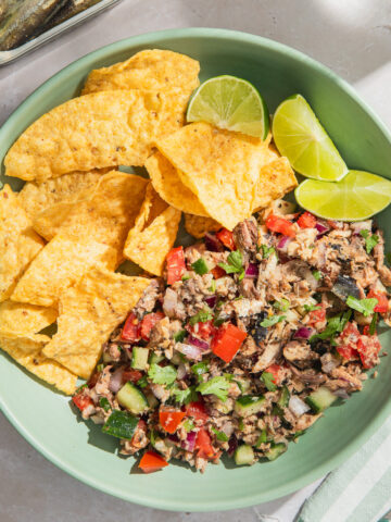 sardines ceviche served with tortilla chips and lime wedges